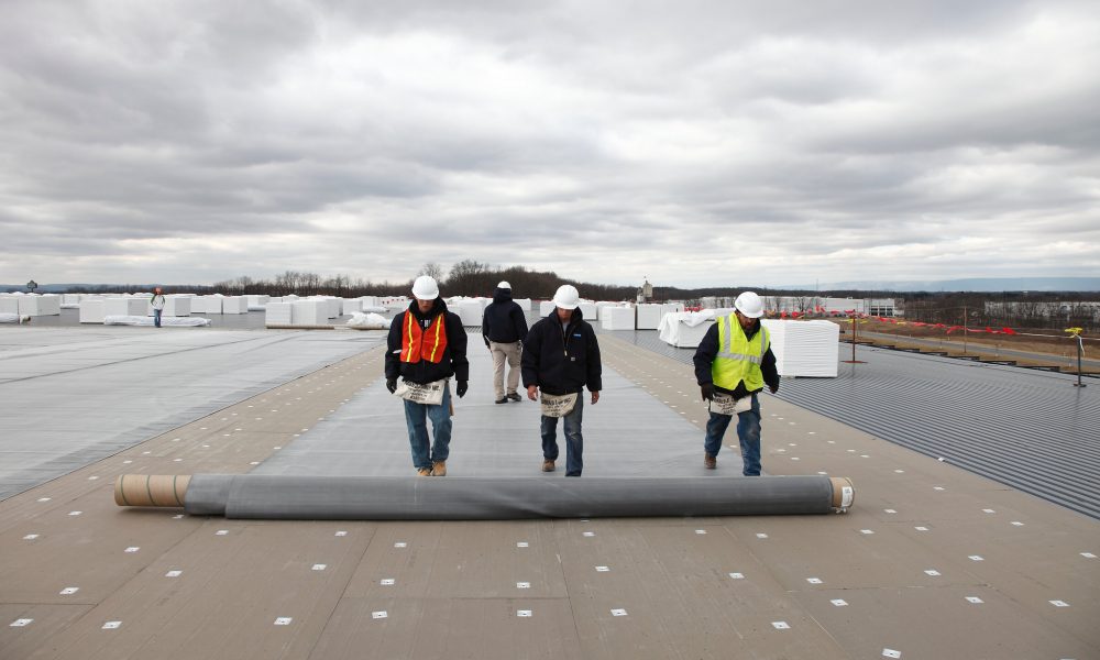 Commercial roofing crew installing a flat roofing membrane.