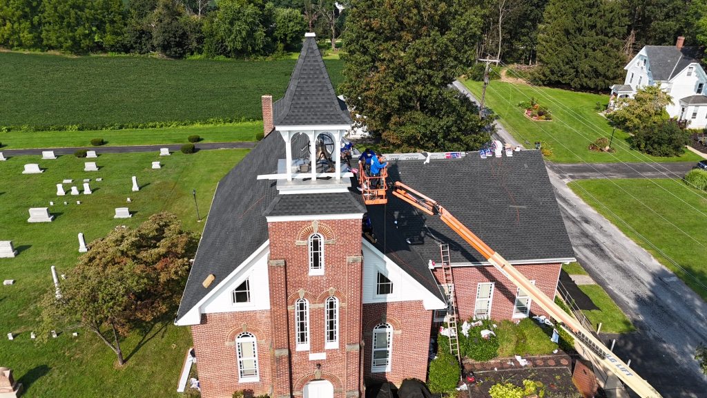 Aerial view of a roof repair crew working from a lift on a large roof.